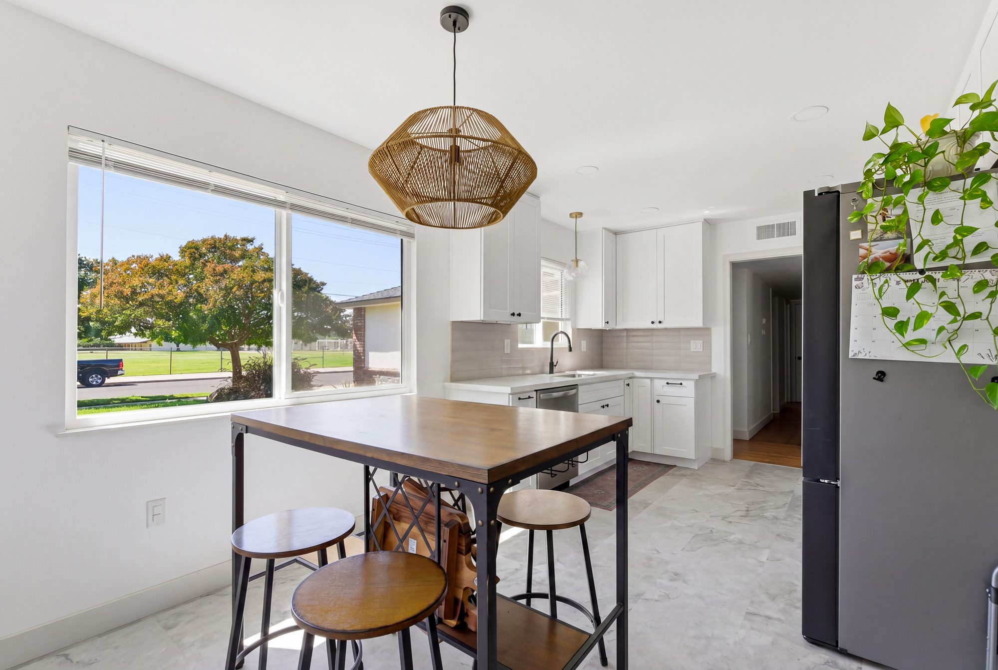 Real estate photography of a white kitchen in Fresno, California, with the window exposure held to keep the exterior view