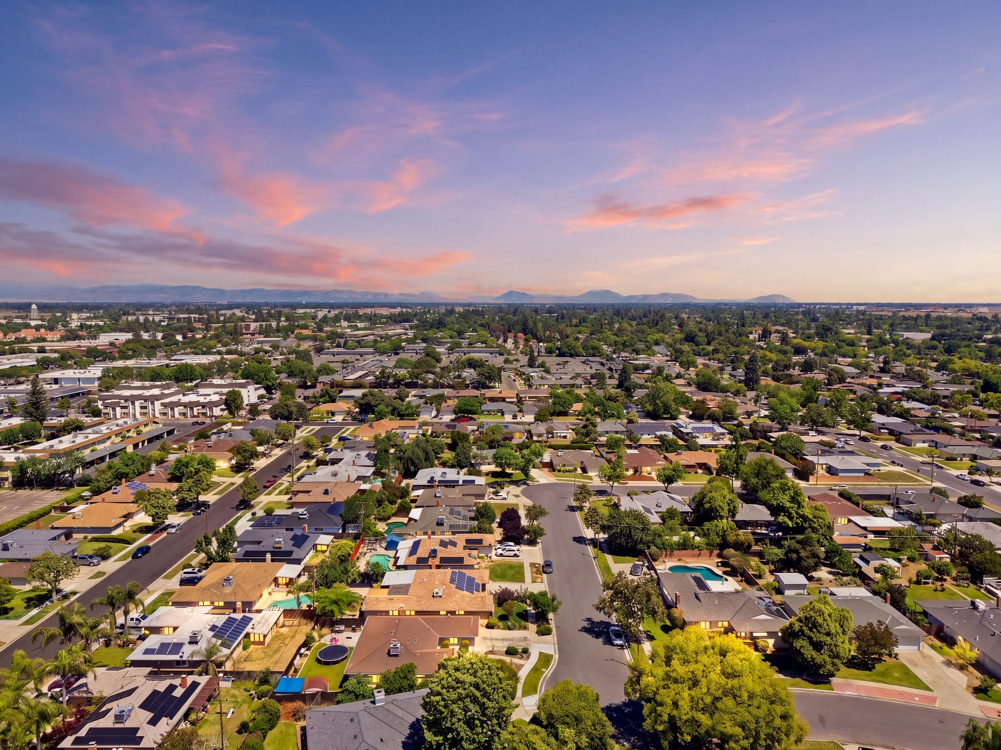 Twilight aerial real estate photography over a Fresno neighborhood with the Sierra foothills on the horizon